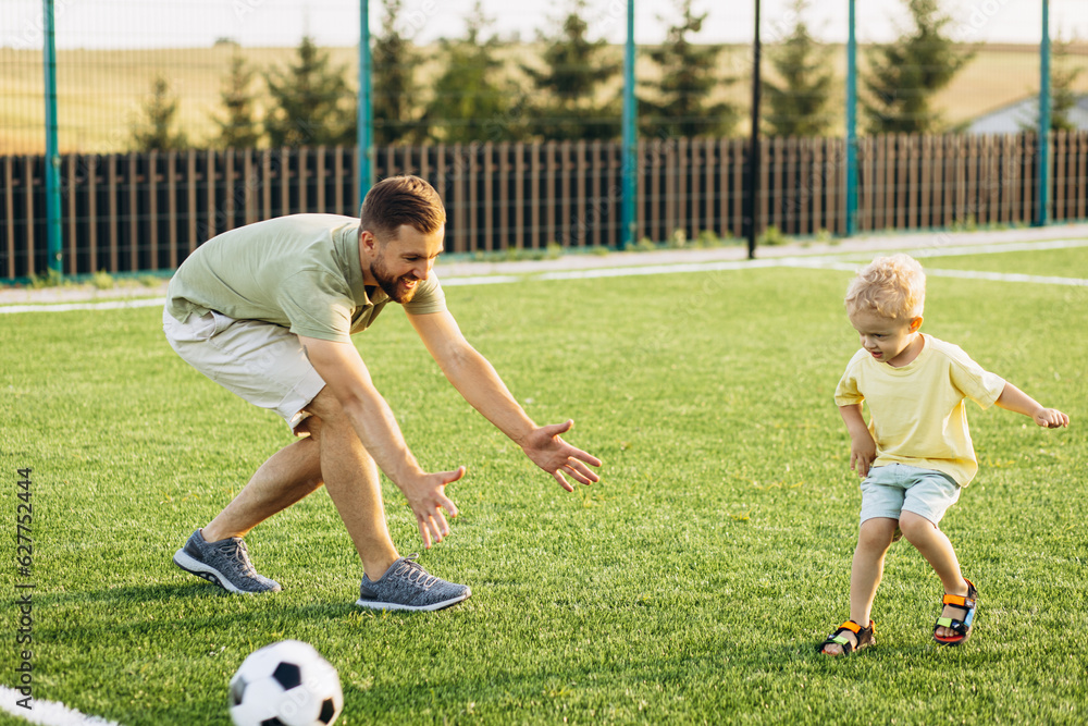 Father with son playing football at the football field Father with son playing football at the football field