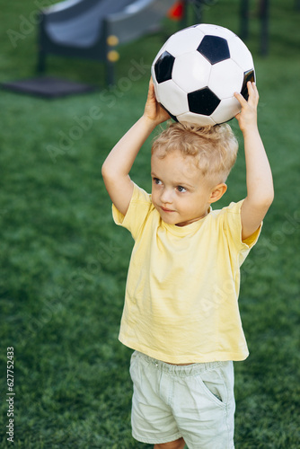 Little boy holding football ball above his head