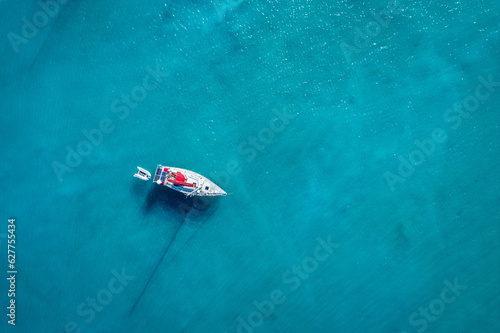 Yacht on lagoon at sunny day. Sailing boat. Yacht in the sea, aerial photography drone. Amazing yacht or sailing boat with a turquoise and transparent sea. Top view of the sailing boats in blue lagoon © daliu
