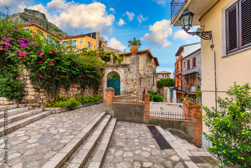 Fototapeta Naklejka Na Ścianę i Meble -  Beautiful old town of Taormina with small streets, flowers. Architecture with archs and old pavement in Taormina. Colorful narrow street in old town of Taormina. Sicily, Italy.