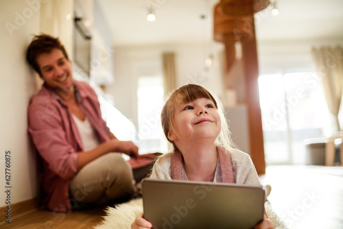 Father and daughter using a digital tablet at home in the kitchen