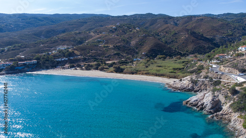 Fototapeta Naklejka Na Ścianę i Meble -  The Livadi Beach at the Ikaria island in a quiet summer day with blue clear water and nature behind, Ikaria, Greece. Little beach lagoon next to the shore.