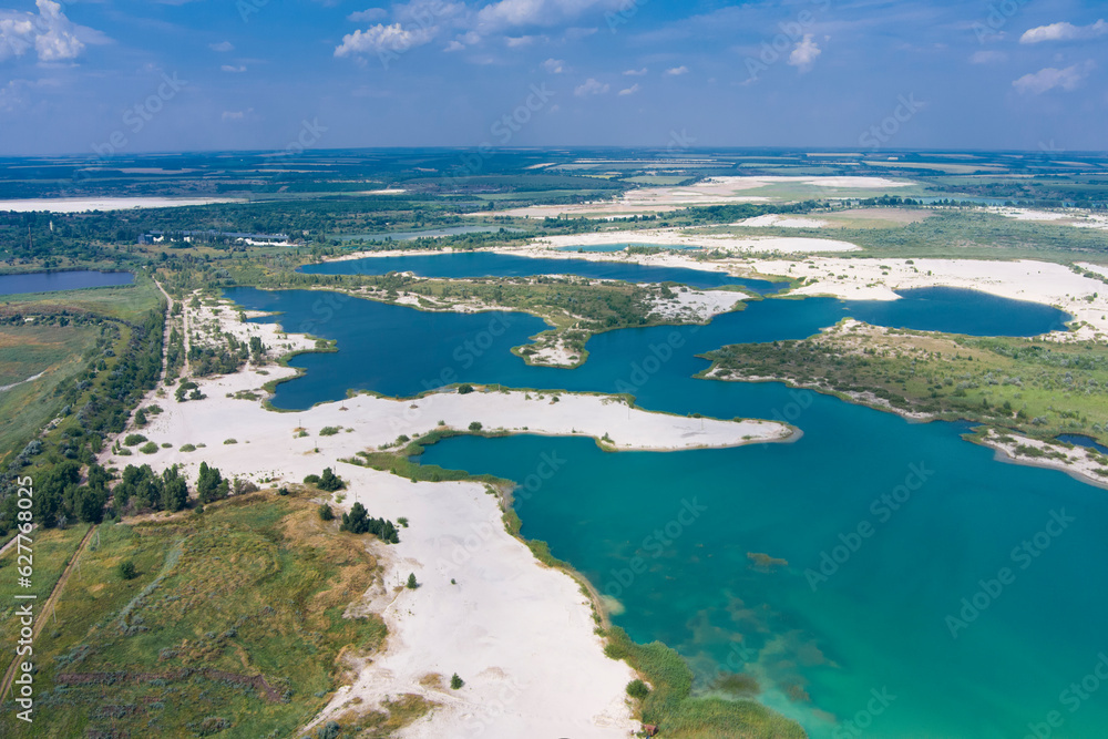 Top view of flooded quarries with white quartz sand. Beautiful artificial lakes with blue water