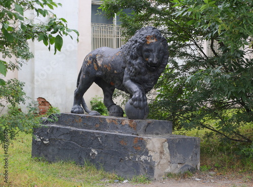 An old broken abandoned lion statue in the roadside bushes, Obukhovskaya Oborona Avenue, Saint Petersburg, Russia, July 26, 2023 photo