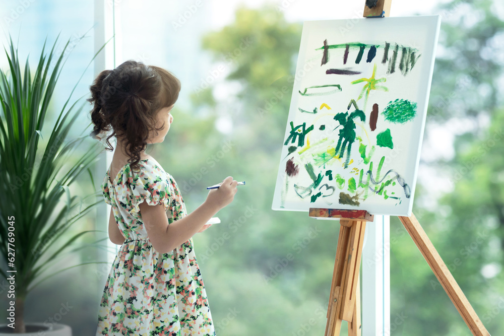 Cute little girl looking at her picture on canvas in living room at ...