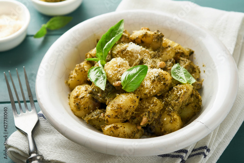 Potato gnocchi. Traditional homemade potato gnocchi with sauce pesto, kitchen table and basil on old rustic turquoise kitchen table. Traditional Italian food. Traditional Italian food. Top view.