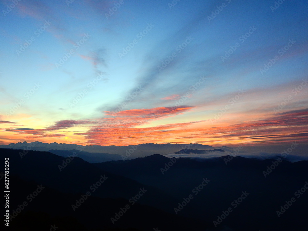 Amanecer de cielo azul y nubes rojas sobre las montañas cantábricas 