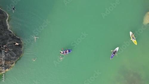 Aerial view of canoe boats in mountain river with turquoise water with rock cliffs. People kayaking, canoeing, and swimming in Kedung Jati Parang, Selopamioro, Imogiri, Bantul, Yogyakarta. 4k footage photo