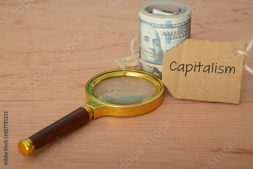 Magnifying glass and money banknotes with text CAPITALISM.