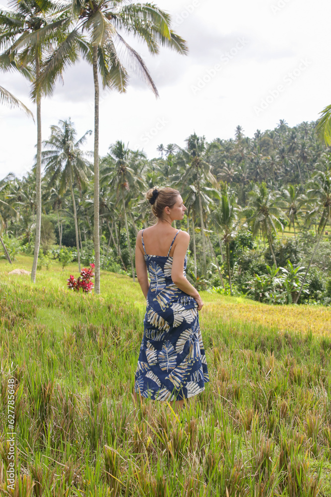 Outdoor fashion portrait of young woman in the rice field on the tropical island with beautiful coconut palm trees,natural sunlight. Concept of freedom, travel, enviroment, connecting with nature Outdoor fashion portrait of young woman in the rice field on the tropical island with beautiful coconut palm trees,natural sunlight. Concept of freedom, travel, enviroment, connecting with nature