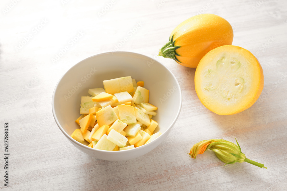 Yellow ball zucchini, whole, chopped in a bowl and an edible flower, ingredient for various vegetable dishes, vegetarian cooking concept, copy space, selected focus Yellow ball zucchini, whole, chopped in a bowl and an edible flower, ingredient for various vegetable dishes, vegetarian cooking concept, copy space, selected focus