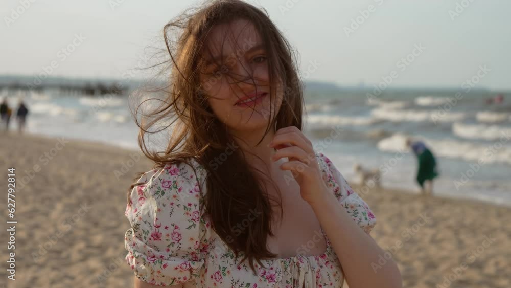 Portrait of young smiling woman walking enjoying peaceful atmosphere on fresh air relaxing at sunset sea beach, touching long hair. Relax leisure activity, active lifestyle, cheerful confident Portrait of young smiling woman walking enjoying peaceful atmosphere on fresh air relaxing at sunset sea beach, touching long hair. Relax leisure activity, active lifestyle, cheerful confident