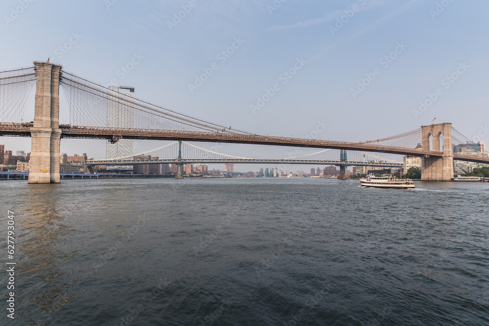 Naklejka premium Brooklyn Bridge and Manhattan bridge with a ferry passing by.