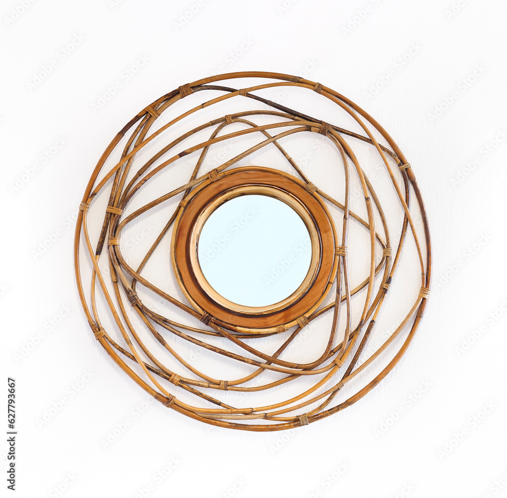 Round mirror in wide wicker rattan frame on white wall, decor element for home interior in colonial style. Handmade rattan weaving furniture from twisted twigs. Round mirror in wide wicker rattan frame on white wall, decor element for home interior in colonial style. Handmade rattan weaving furniture from twisted twigs.