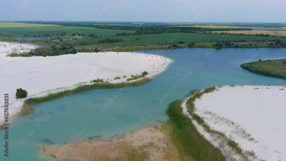 Top view of a flooded white quartz sand quarry (camera pans forward). Beach on an artificial lake Top view of a flooded white quartz sand quarry (camera pans forward). Beach on an artificial lake