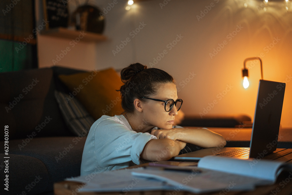 Tired depressed young woman working at home at night on a project using a laptop. Problems with long hours workaholism Tired depressed young woman working at home at night on a project using a laptop. Problems with long hours workaholism