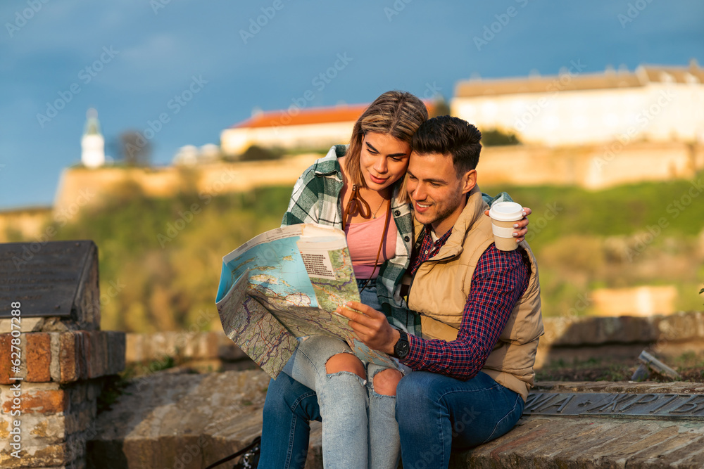 a couple in love, a girlfriend sits on a boyfriend's lap while they read a map and take a break from sightseeing a couple in love, a girlfriend sits on a boyfriend's lap while they read a map and take a break from sightseeing