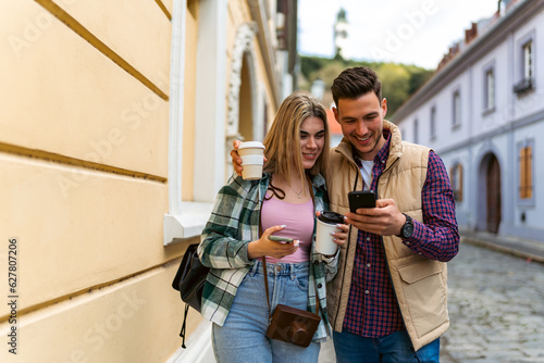 tourists walk around the city hugging each other, drinking coffee to go and using online maps on their phones © DusanJelicic