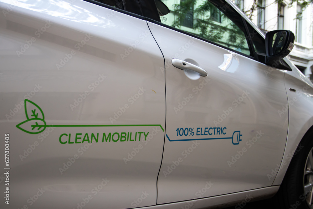 Fototapeta premium Electric vehicle (EV) connected on plug for charging, Clean mobility, 100% electric, reduction of CO2 and green energy, eco and environmental friendly, renewable energy