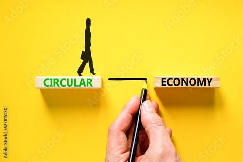 Circular economy symbol. Concept words Circular economy on beautiful wooden block. Beautiful yellow table yellow background. Businessman hand. Business circular economy concept. Copy space.