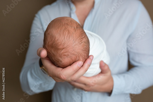 Father holding head of her newborn baby in hands. Loving father hand holding cute sleeping newborn baby child. Beautiful conceptual image of parenthood