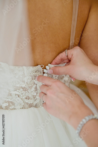 The bride fastens her dress. Close-up.