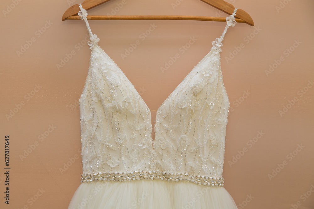 The delicate bride's dress is hanging in room. Selective focus. Close-up. The delicate bride's dress is hanging in room. Selective focus. Close-up.