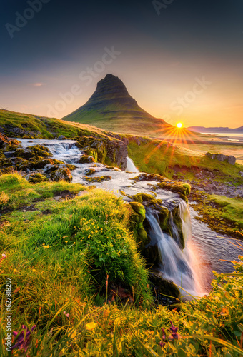 Fototapeta Naklejka Na Ścianę i Meble -  Sunrise over Kirkjufell mountain with waterfall flowing and wildflower blooming in summer at Iceland