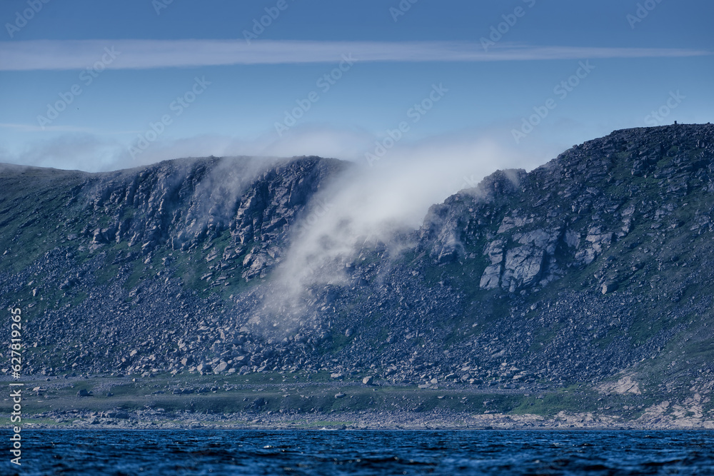 Dramatic sea fog rising trough hole in a ridge in Knivskjelodden that the real northernmost point of Europe and close close to North Cape in August 2022.