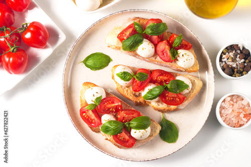 Tomato, basil and mozzarella cheese fresh made caprese bruschetta. Italian tapas, antipasti with vegetables, herbs and oil on grilled ciabatta and baguette bread. Open sandwich.