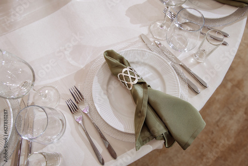 Plates with fabric napkin, decorative ring and cutlery on light gray marble table, flat lay. High quality photo