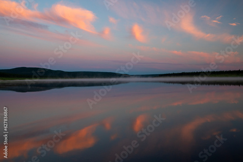 Sunset tranquility, pink clouds reflecting in the still river 