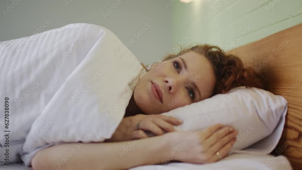 A young redheaded beautiful woman wakes up In the morning. Sun rays fall on her smiling face. Close Up A young redheaded beautiful woman wakes up In the morning. Sun rays fall on her smiling face. Close Up