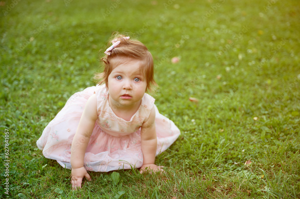 Adorable girl on the grass in the garden. Close up portrait. Happy little girl in summer scenery. Sweet small kid outdoors. Adorable girl on the grass in the garden. Close up portrait. Happy little girl in summer scenery. Sweet small kid outdoors.