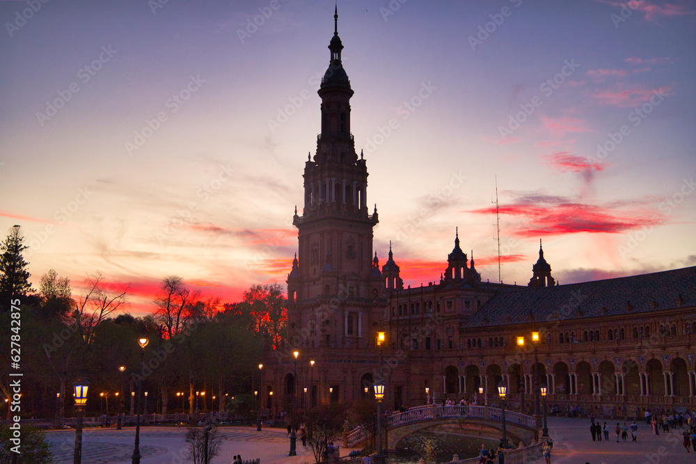 Naklejka premium Night view of the monument of plaza de spain in seville, spain. Reddish sky at sunset in the city.