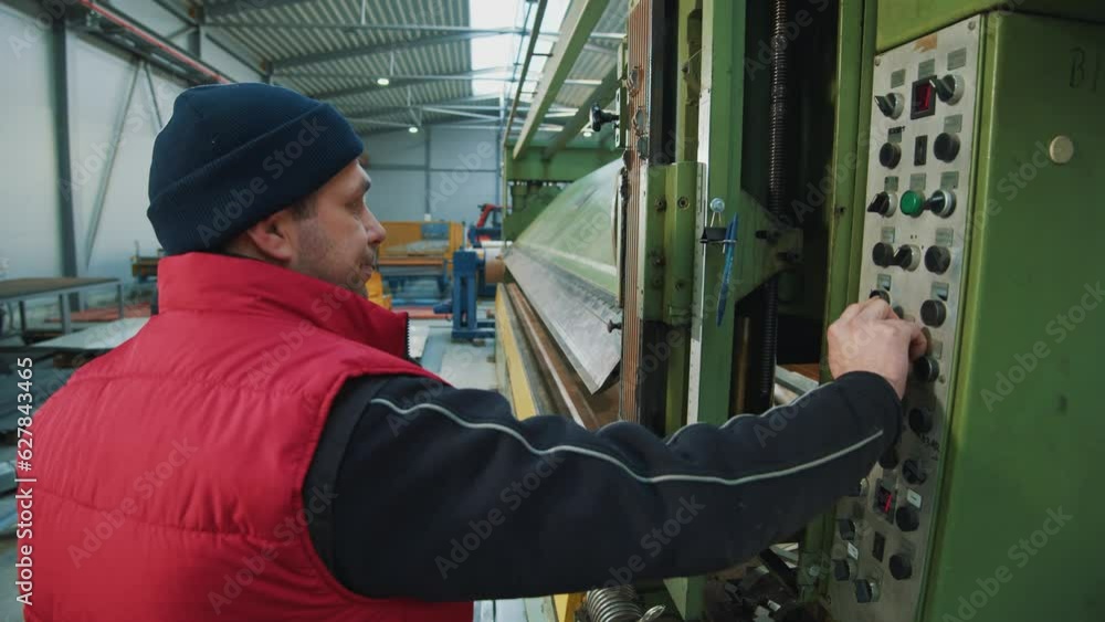 Shot back engineer man in safety uniform stand presses buttons during the production process in factory. Inspector in warehouse. Shot back engineer man in safety uniform stand presses buttons during the production process in factory. Inspector in warehouse.