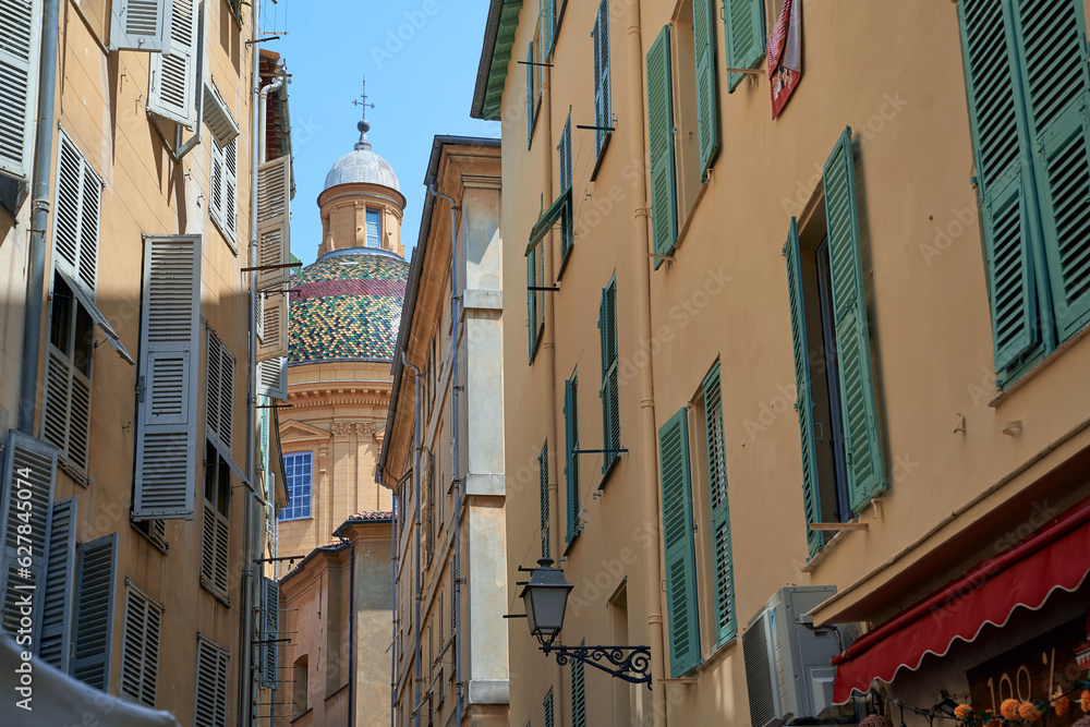 Narrow street in the old town in Nice France with a view of Saint Reparate Cathedral dome
