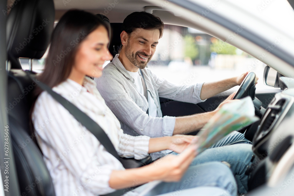 Happy millennial couple having car trip together, reading map