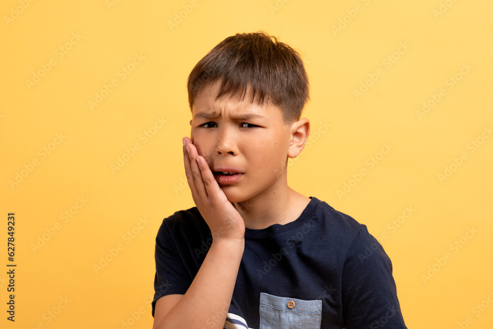 Portrait of unhealthy school aged boy touching cheek Portrait of unhealthy school aged boy touching cheek