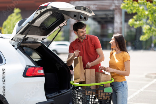 Millennial spouses packing car trunk with groceris