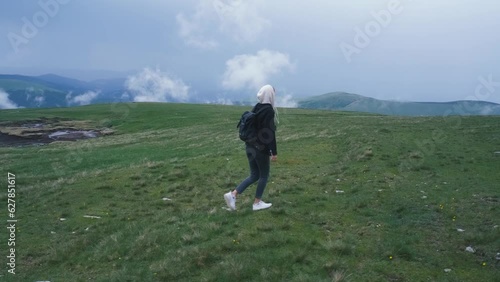 A beautiful Ukrainian young woman traveler walks along the most beautiful high mountain road in Romania Transalpina highway at cold dayt. Transalpina, Carpathian mountains in Romania at day. Slow photo