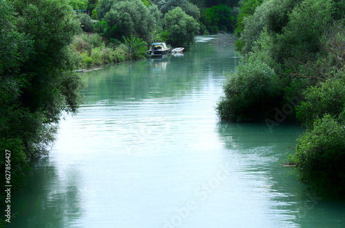 barche nel fiume con fitta vegetazione che attraversa la citta  photo
