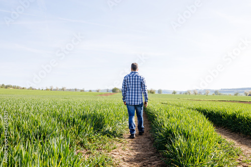 A man stands in a field and enjoys the silence  unity with nature. Male farmer walking in the harvest field