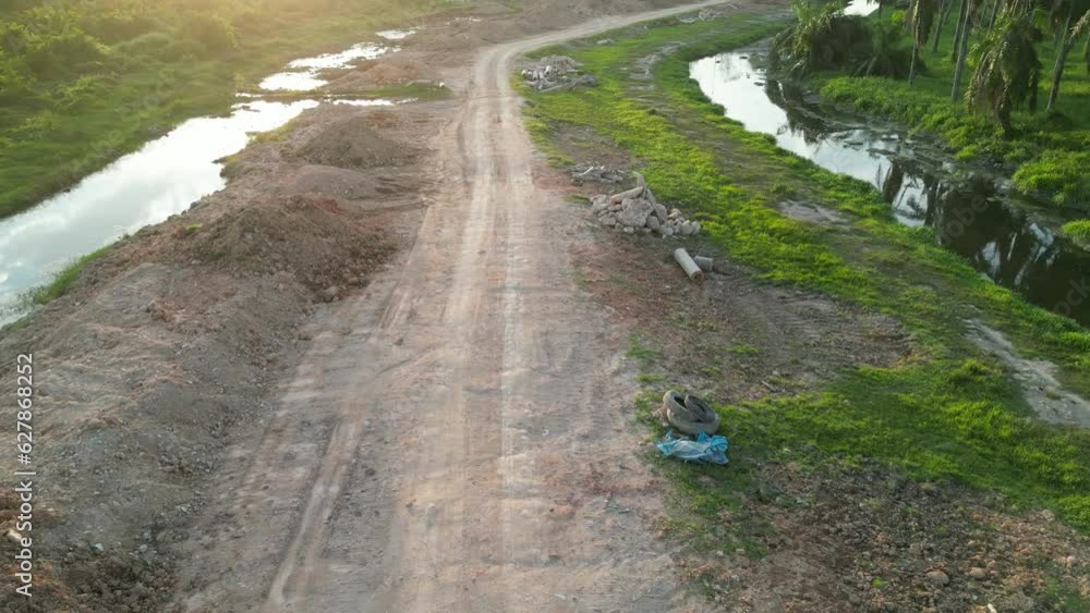 Scenic dirt road winding alongside a river from an aerial perspective Scenic dirt road winding alongside a river from an aerial perspective