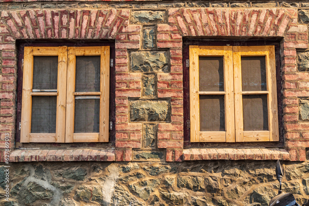 Wood framed windows in a brick and stone building.