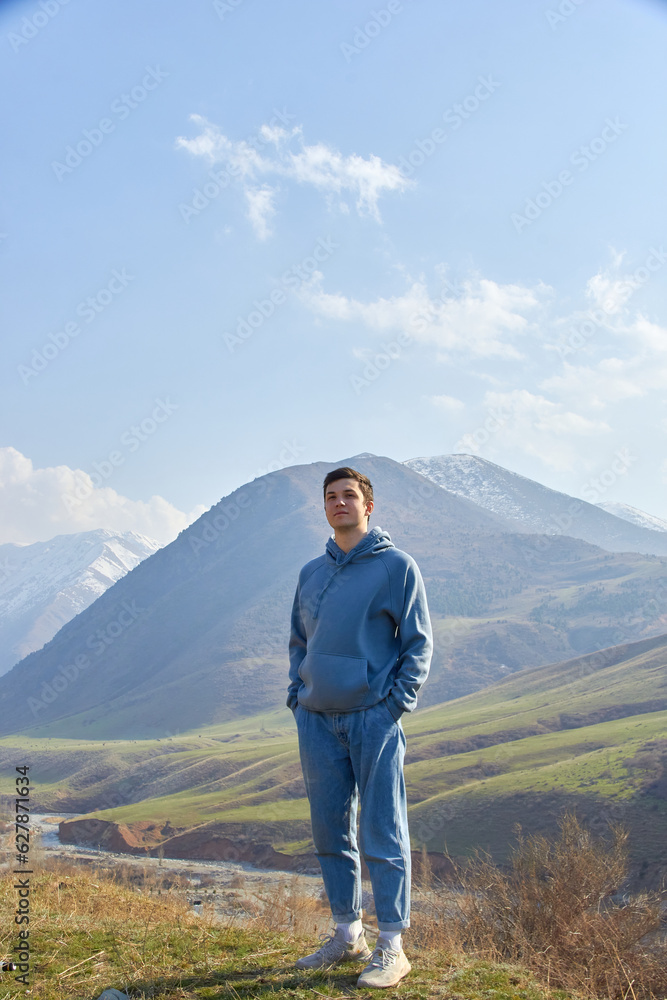 teenager against the backdrop of the mountains after climbing portrait of a cheerful boy in the highlands