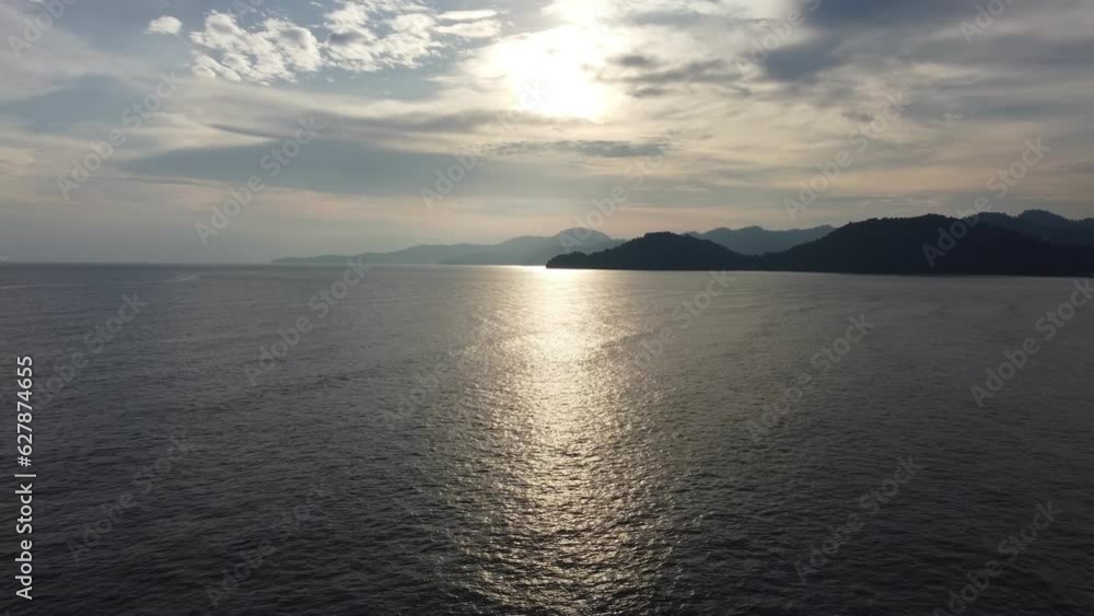 Serene sea surrounded by majestic mountains at background during sunset Serene sea surrounded by majestic mountains at background during sunset