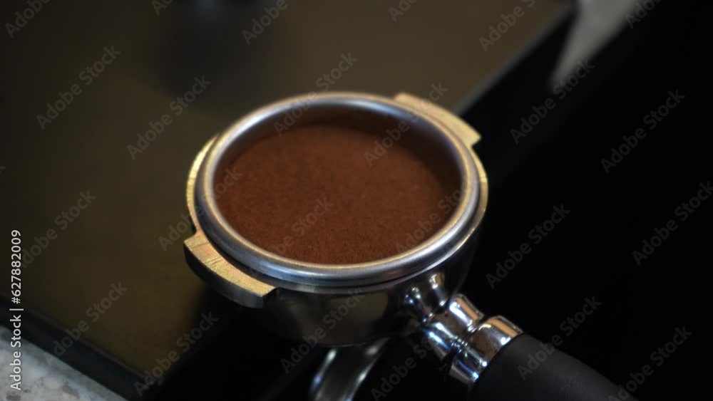 Preparation of ground coffee with tamping of fresh coffee. Tamper of freshly ground coffee. A barista's hand holds and presses the ground coffee powder in a portafilter, ready to make a cup of coffee. Preparation of ground coffee with tamping of fresh coffee. Tamper of freshly ground coffee. A barista's hand holds and presses the ground coffee powder in a portafilter, ready to make a cup of coffee.