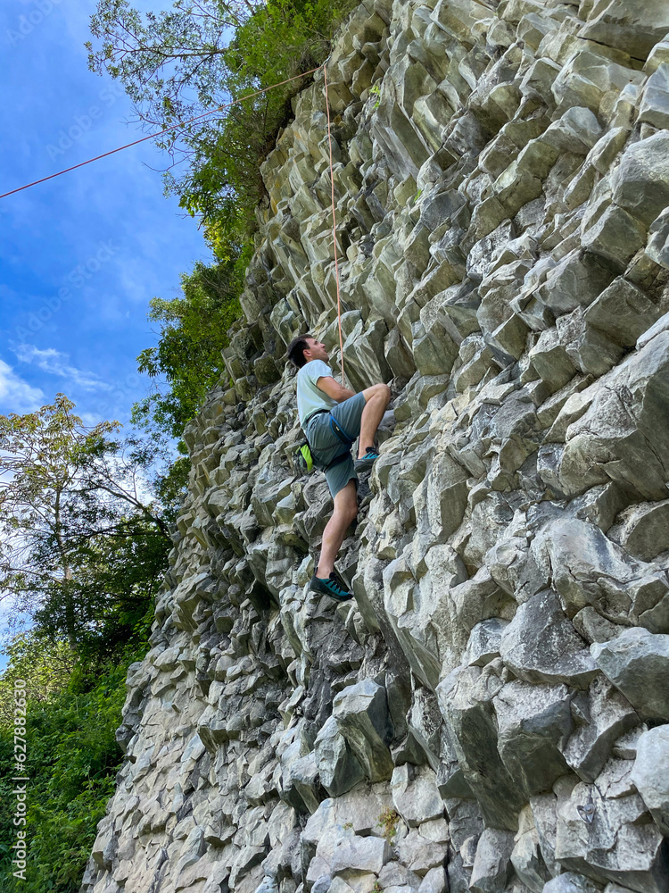Adrenaline seeking vacationer in Panama top rope climbing a volcanic basalt wall
