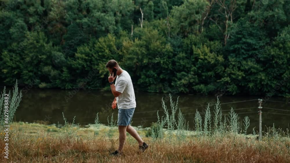 Sportive mid-aged Caucasian man walks in the nature. Man starts a conversation on his phone. Sportive mid-aged Caucasian man walks in the nature. Man starts a conversation on his phone.